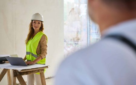 Builder looking at realtor standing near table with laptop